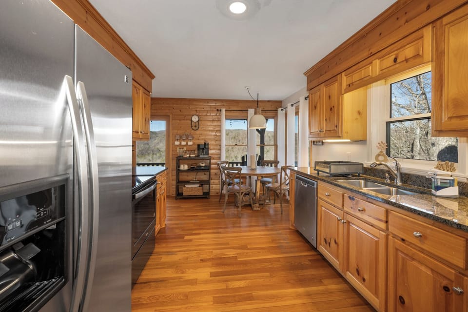 Your fully equipped kitchen features warm wood cabinets, granite counters, and stainless steel appliances, perfect for preparing meals while enjoying mountain views.