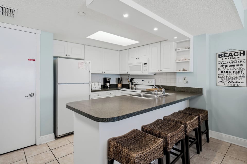 Your coastal retreat features a fully equipped kitchen with modern appliances and a spacious breakfast bar—perfect for morning coffee or casual meals.