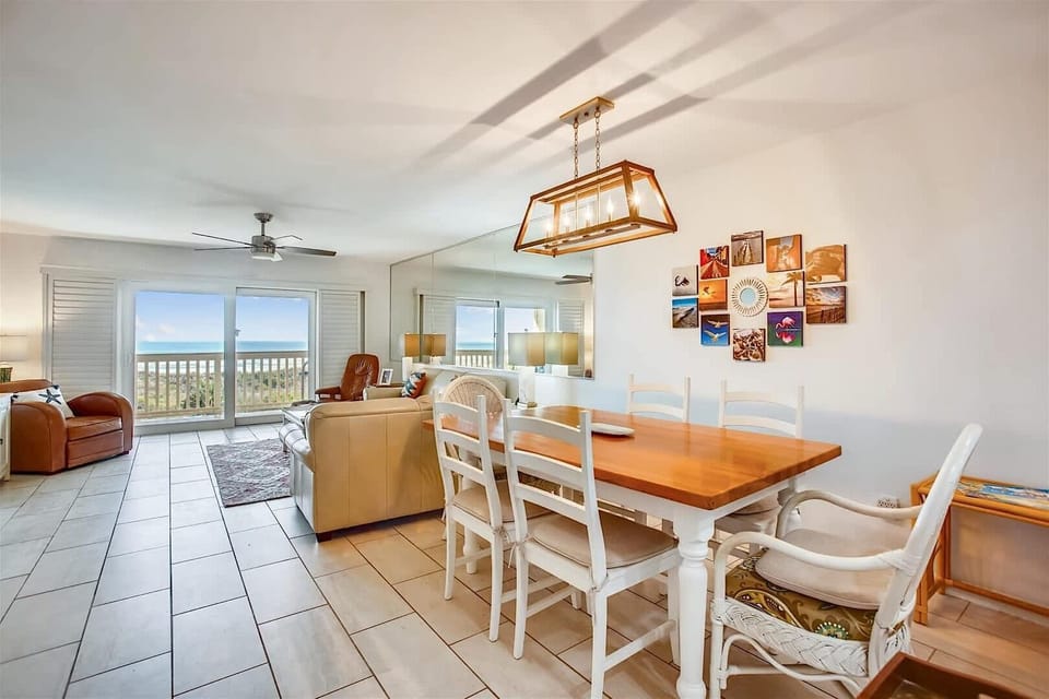 - Bright and airy dining space next to large windows bringing in natural light  
- Comfortable seating and rustic wood table ideal for memorable vacation meals  
- Conveniently located near kitchen and living room with ocean views nearby