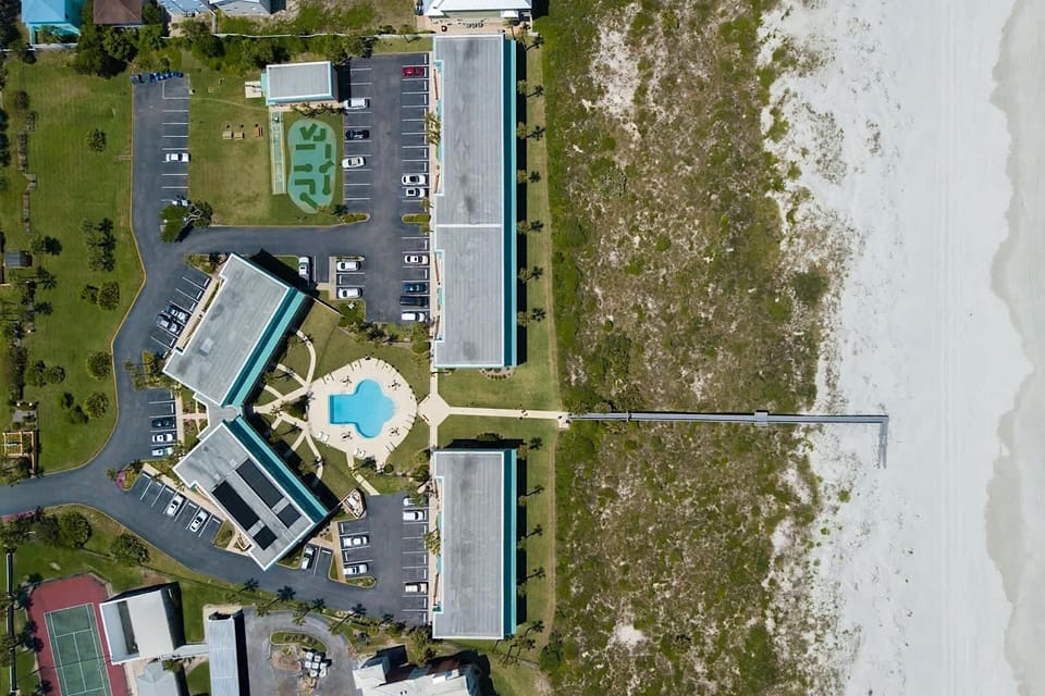 - Aerial resort view shows direct beachfront access with private walkway to sand  
- Pool centered among buildings offering convenience and recreation  
- Scenic combination of beach, amenities, and comfort for vacation stays
