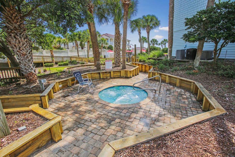 Cozy hot tub area surrounded by palm trees and seating.