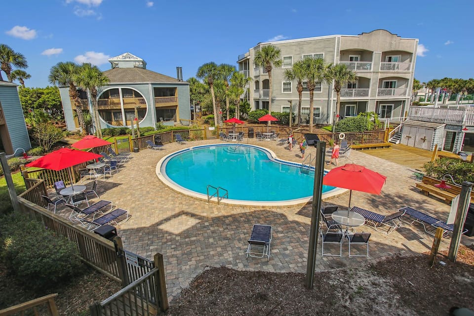 Elevated pool view with shaded seating and tropical landscaping.