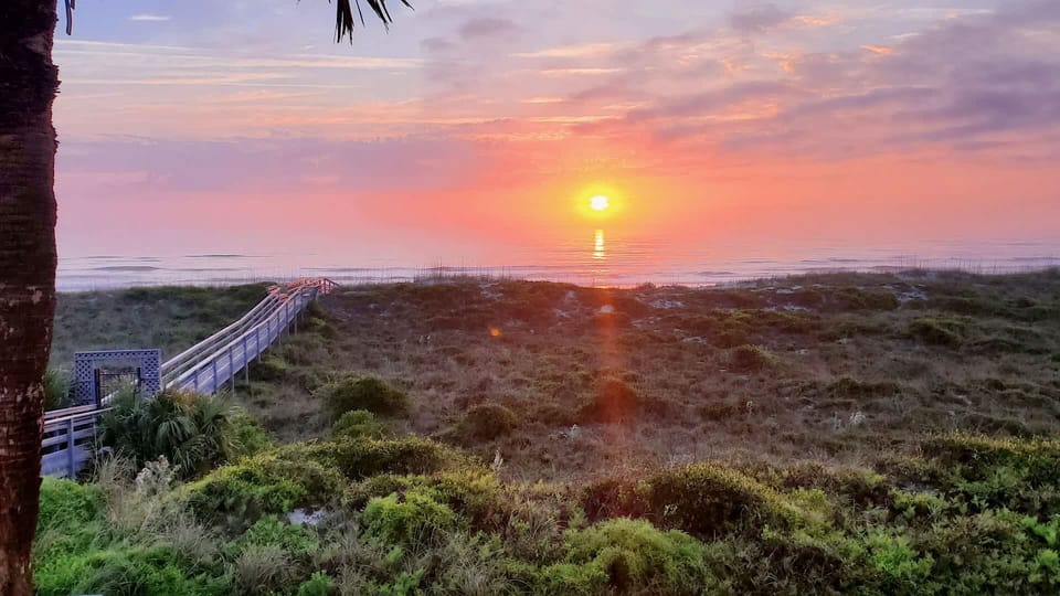- Stunning sunrise view from the property overlooking dunes and beach  
- Wooden boardwalk leads directly to the sandy shoreline below  
- Perfect way to start mornings with breathtaking coastal scenery

