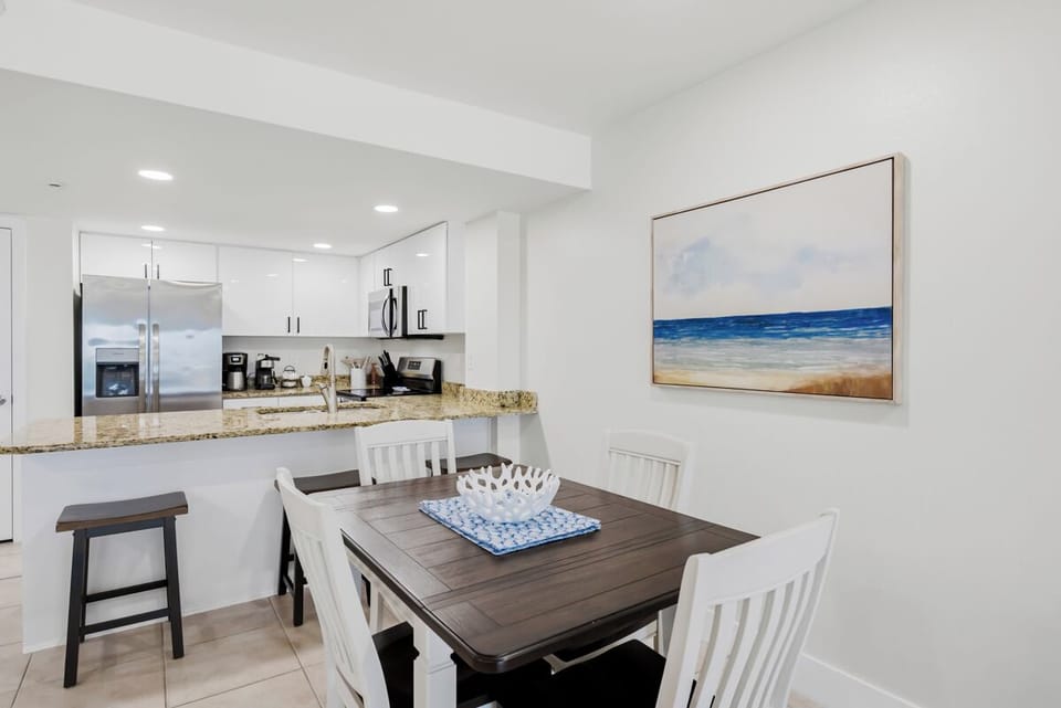 Gather around your bright dining space, where modern convenience meets coastal charm. The open kitchen invites easy entertaining.