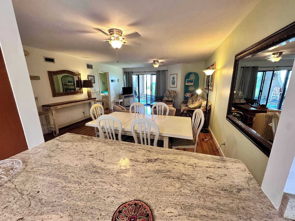 - Enjoy an open layout where the kitchen connects seamlessly to dining and living
- White dining table seats six with a mirror reflecting soft coastal tones
- Great for gathering after the beach with light, space, and flow throughout