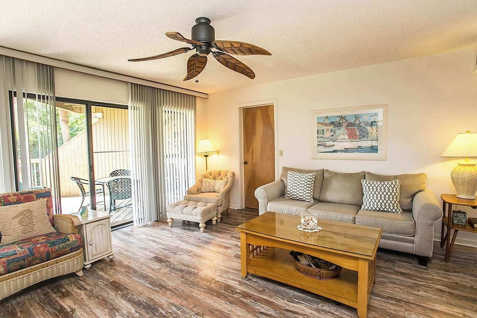 - Comfortable living room with sofa, chairs, and a ceiling fan for relaxation
- Sliding glass doors lead to the patio creating seamless indoor outdoor flow
- Neutral decor and stylish accents create a calming coastal retreat