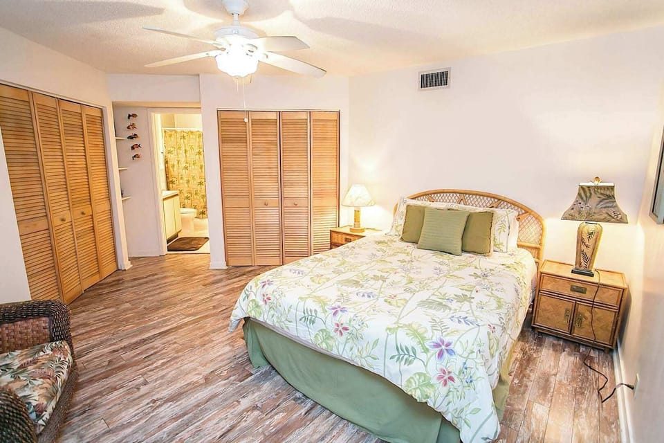 - Cozy bedroom with queen bed, wicker headboard, and matching nightstands
- Ceiling fan and soft lighting create a warm and restful environment
- Spacious closets and ensuite bath access add comfort and convenience