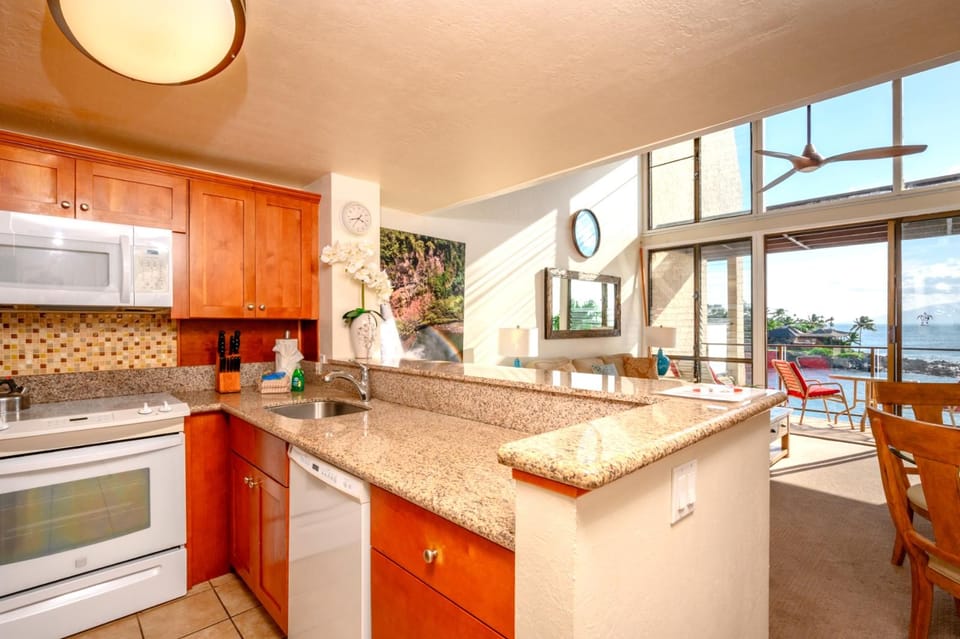 This cheerful kitchen features honey-toned wood cabinets, granite counters, and a breezy open view to the lanai