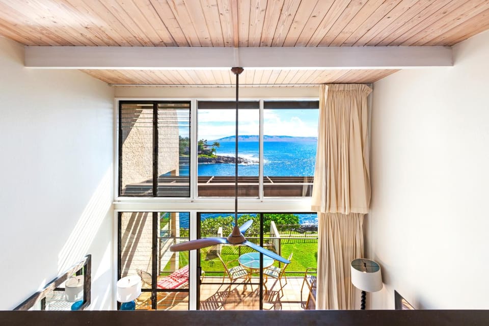 Sunlight pours through two-story glass, dancing across coastal décor and views that stretch far beyond the lanai