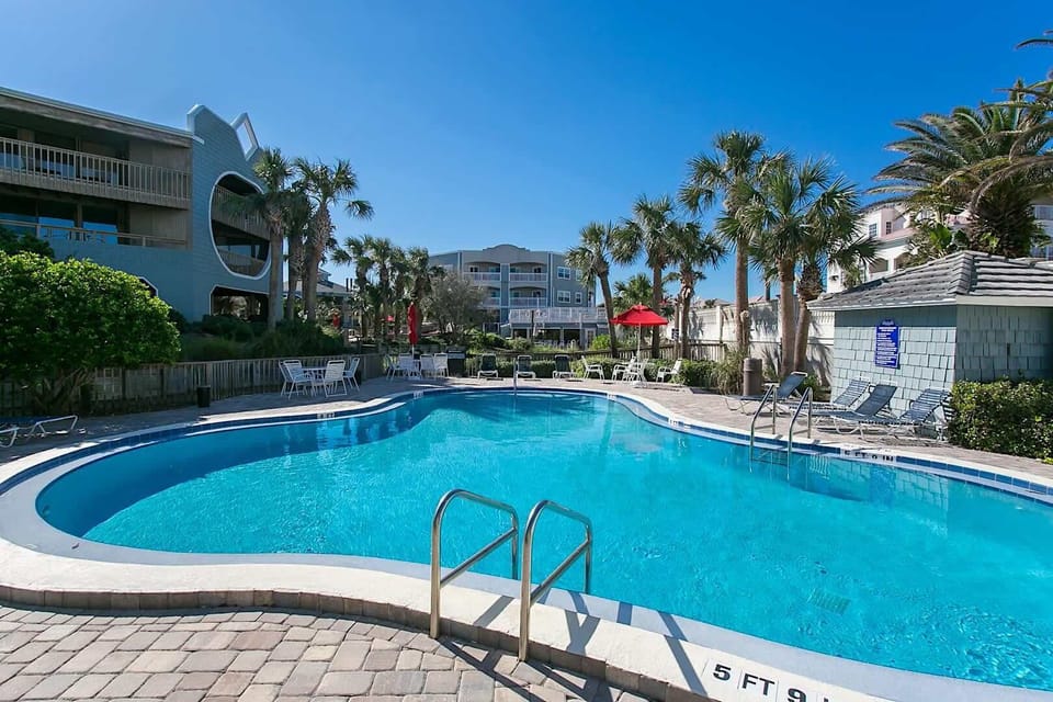 Resort pool with steps, loungers, and tropical landscaping.