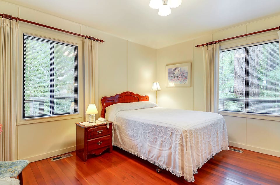 Downstairs - Primary bedroom: Queen bed with antique headboard and side table.