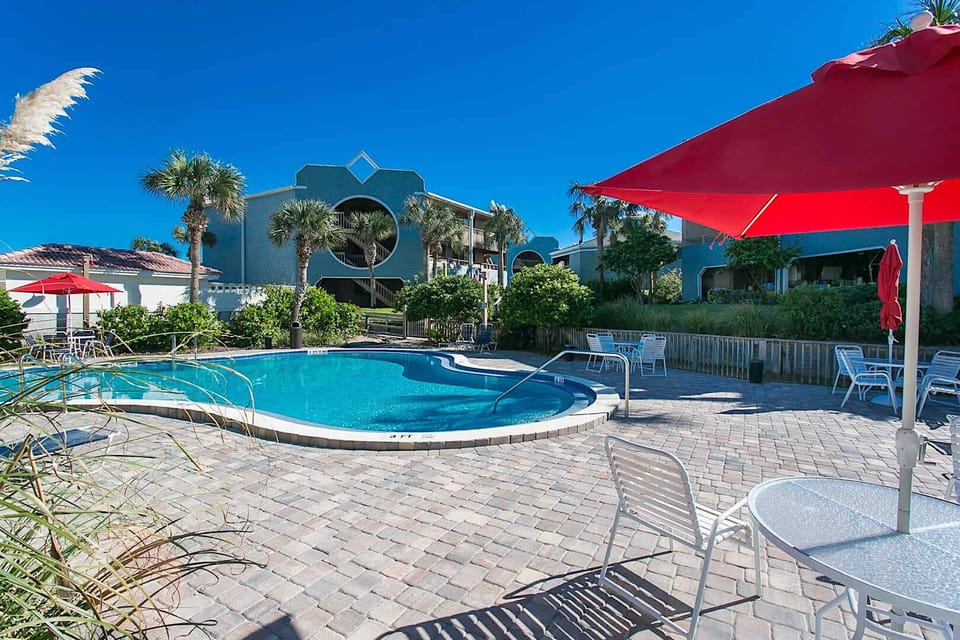 Sip and relax under red umbrellas beside this beautiful resort style pool.