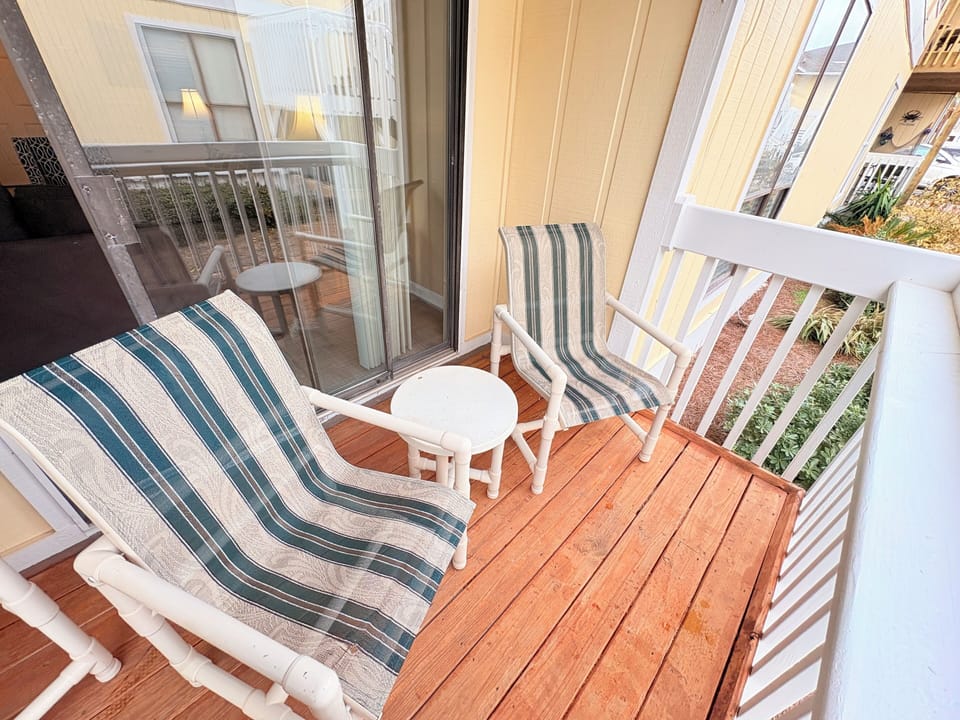 Step onto your private balcony where coastal-striped chairs invite you to unwind with morning coffee on warm wood decking.