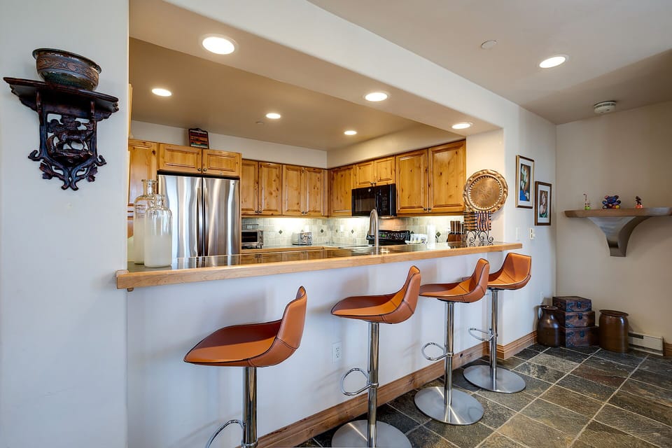 Gather around your spacious kitchen island with stylish orange bar stools, perfect for morning coffee or casual dining together.