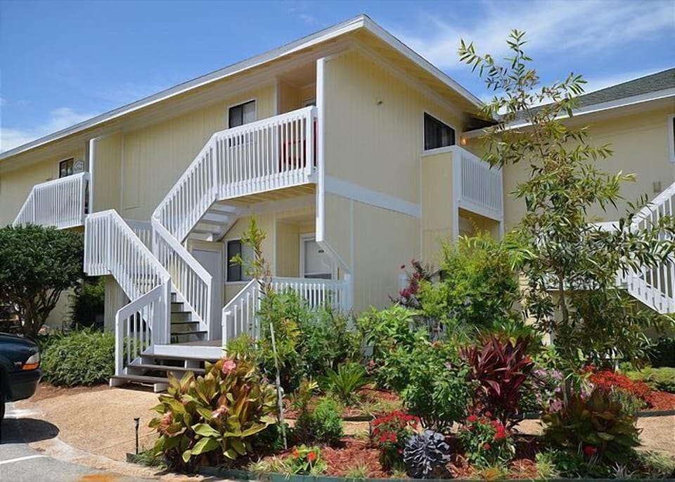 A bright vacation property featuring tropical landscaping and convenient stair access to second-floor units.