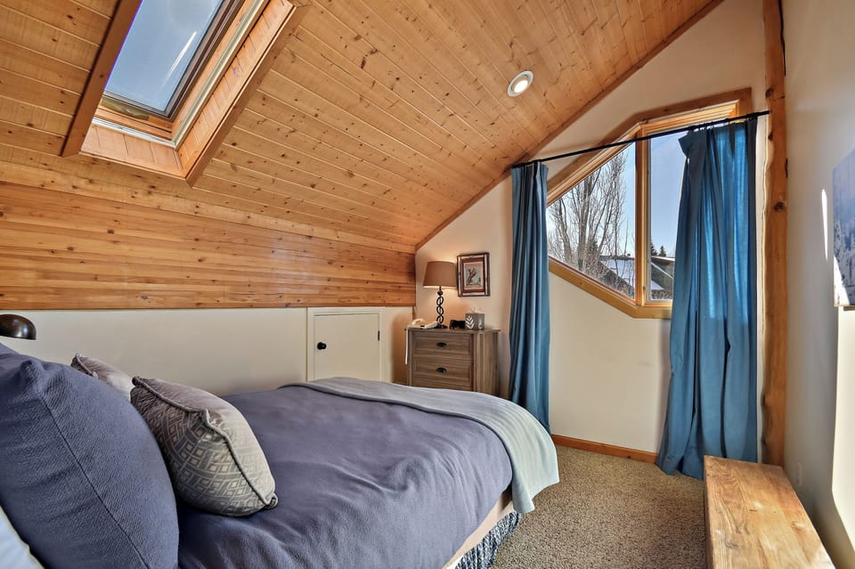 Your cozy attic retreat features exposed wood beams and a skylight above your bed, filling the space with natural warmth and mountain light.