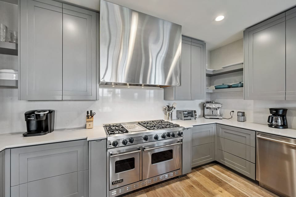 Your gourmet kitchen features premium stainless steel appliances, elegant grey cabinetry, and marble countertops perfect for preparing memorable meals during your stay.