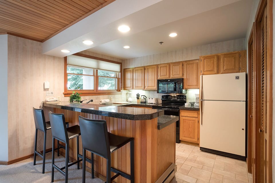 Your fully equipped kitchen features warm wood cabinetry, granite countertops, and a breakfast bar where you can start each day.