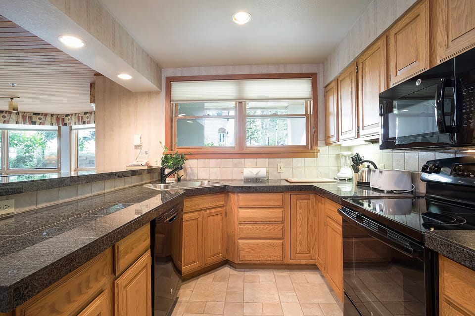 Your fully equipped kitchen features granite counters, rich wood cabinets, and modern appliances for preparing memorable meals together.