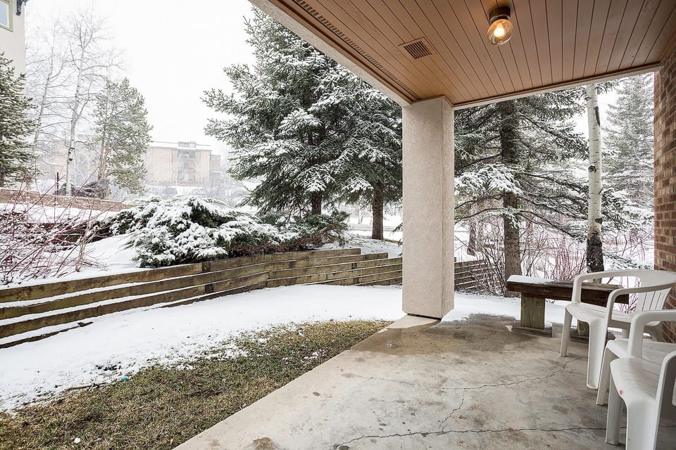 Your covered patio offers peaceful seating with snowy evergreen views, perfect for morning coffee while watching winter's beauty unfold outside.