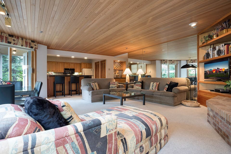 Settle into your spacious open-concept living area where warm wood ceilings meet modern comfort, perfect for relaxing after mountain adventures.