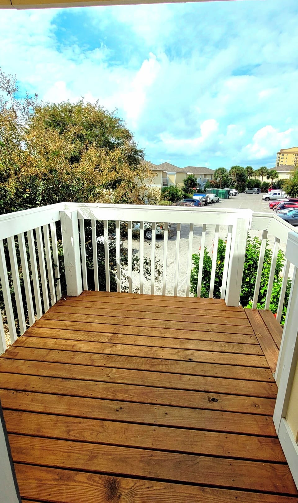 Step onto your private balcony with warm wood decking and white railings, where blue skies and neighborhood views await your morning coffee moments.