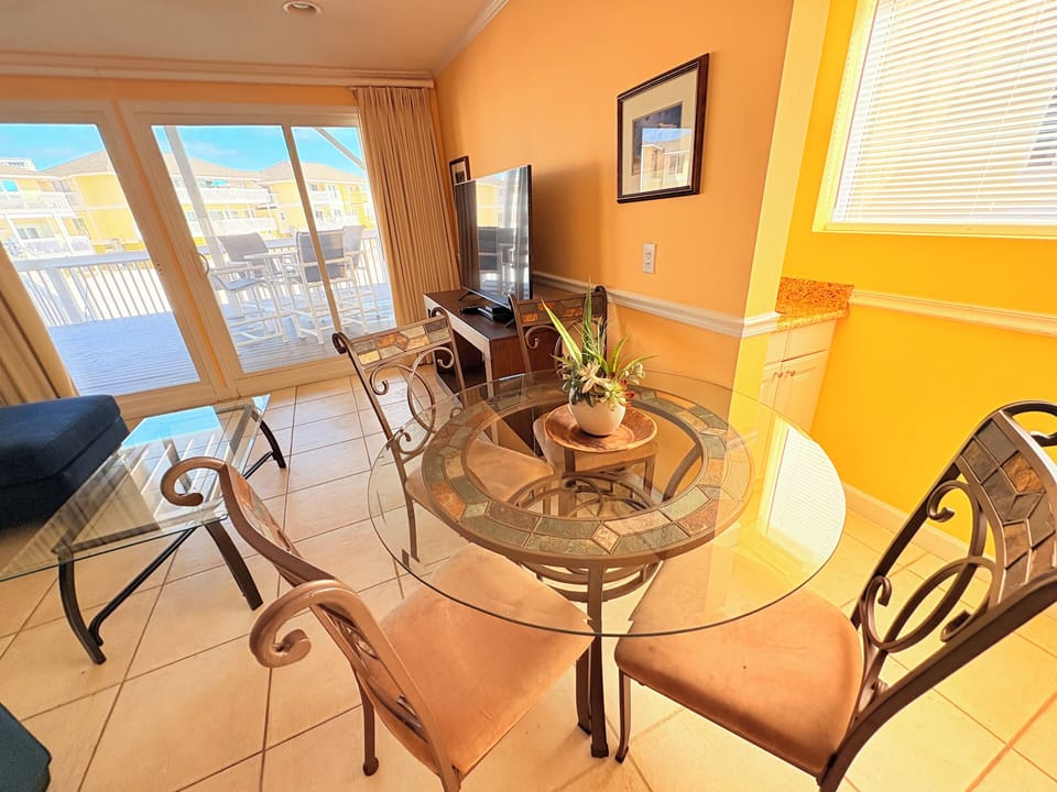 Gather around your elegant glass dining table while warm sunlight streams through floor-to-ceiling windows, creating the perfect spot for memorable meals.