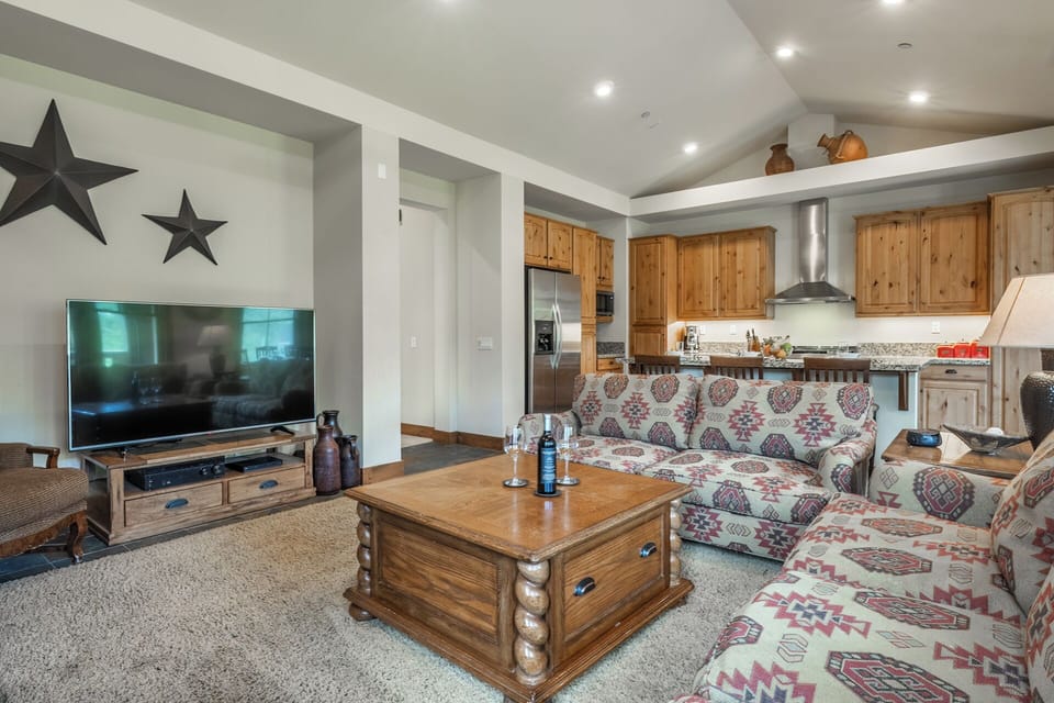 Unwind in your spacious living area with a stylish blend of rustic charm and modern comfort. Cozy seating, warm wood cabinetry, and a fully-equipped kitchen await your arrival.