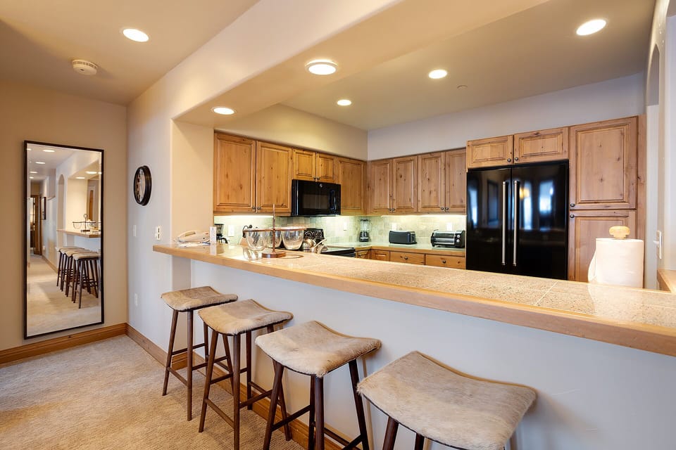 Your spacious kitchen invites culinary adventures with warm wood cabinetry, modern appliances, and a breakfast bar for morning coffee.