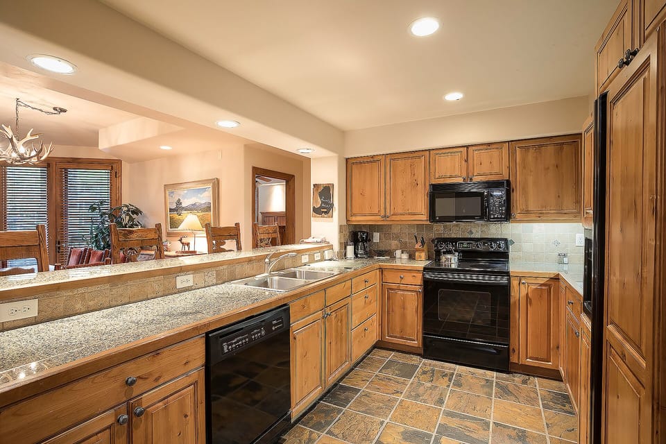 Cook your favorite meals in this spacious kitchen with granite counters, warm wood cabinetry, and modern appliances.