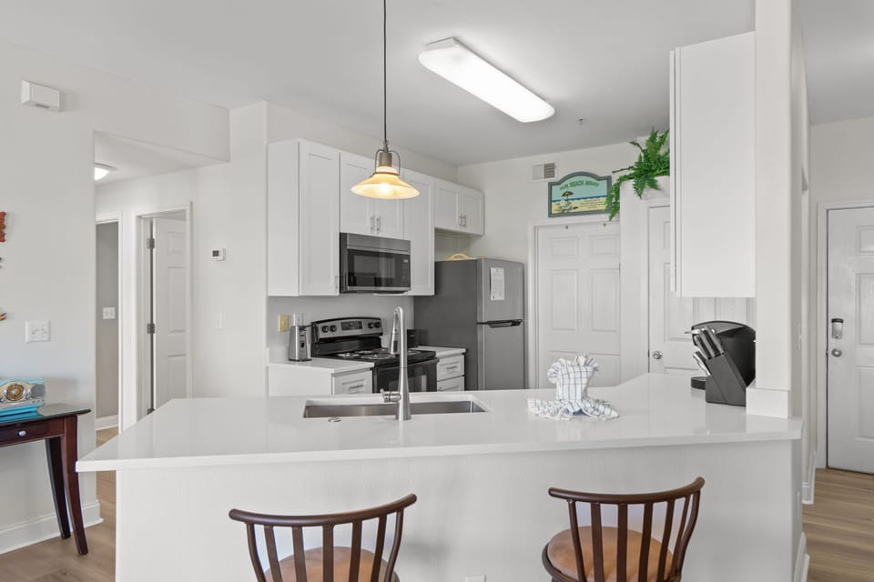 Your bright, modern kitchen awaits with gleaming countertops, stainless steel appliances, and an inviting breakfast bar perfect for morning coffee.