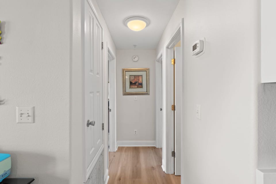 Step into your bright hallway with warm wood floors and thoughtful artwork, creating an inviting pathway to your comfortable rooms.