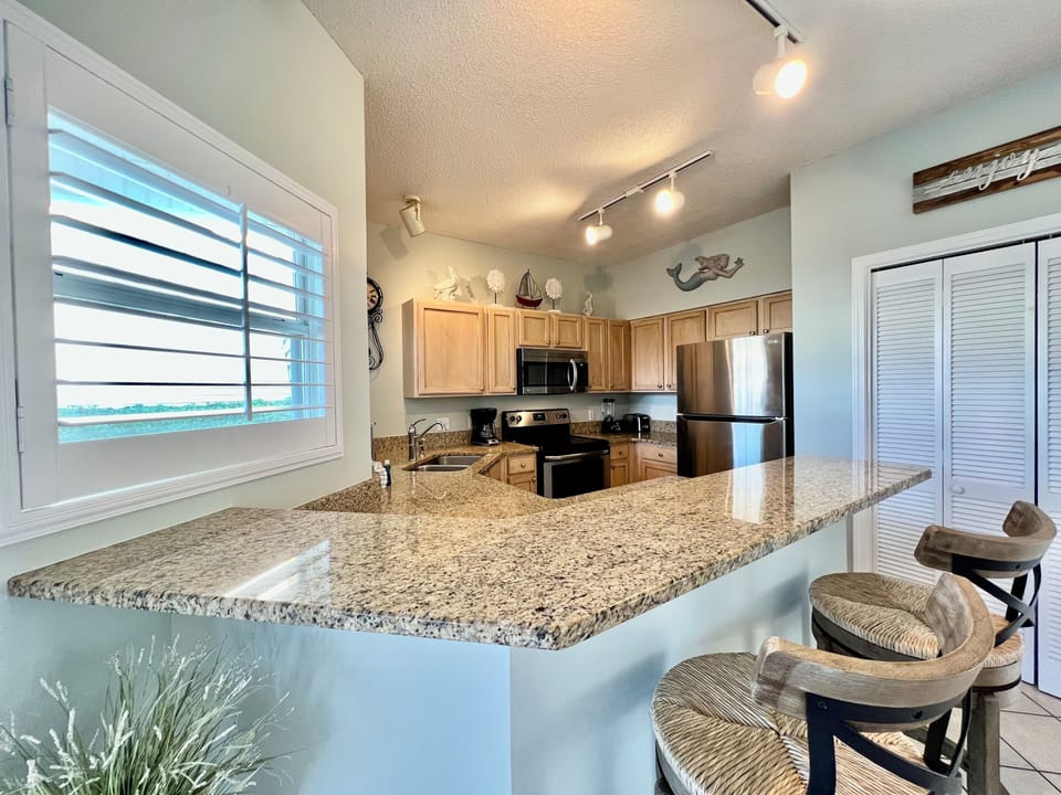 Your modern kitchen awaits with granite counters, stainless appliances, and ocean views streaming through bright windows.