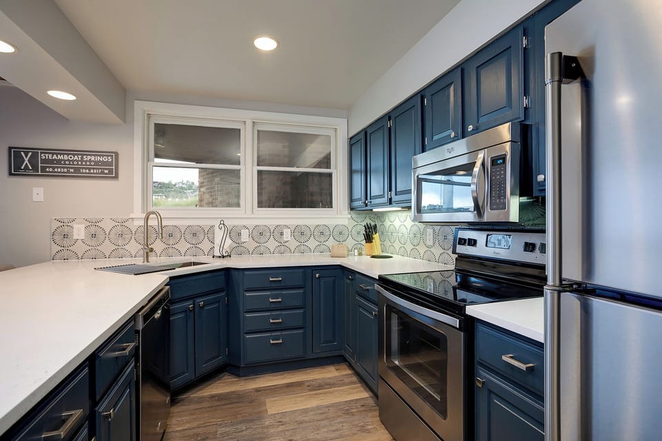 Your modern kitchen features rich navy cabinets, white countertops, and stainless appliances—perfect for preparing home-cooked meals during your stay.