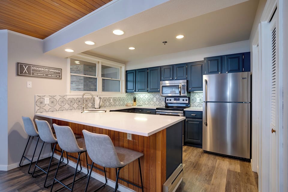 Your fully equipped kitchen features stainless steel appliances, a spacious island with seating for four, and modern finishes perfect for preparing memorable meals.