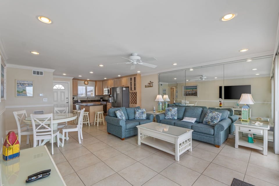 Relax in your spacious open-plan living area with comfortable seating, full kitchen, and coastal-inspired décor perfect for family gatherings.