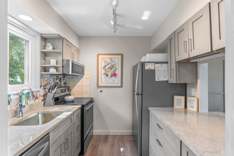 Your fully equipped kitchen features modern appliances and ample counter space for preparing home-cooked meals. Natural light streams in through the garden-view window, brightening this inviting culinary space.