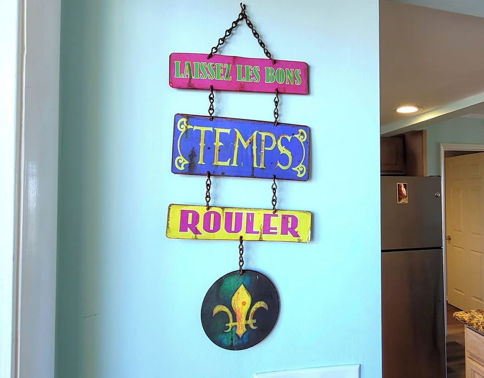 Charming French-inspired wall art welcomes you with colorful 'Laissez Les Bons Temps Rouler' signage, adding playful New Orleans flair to your stay.