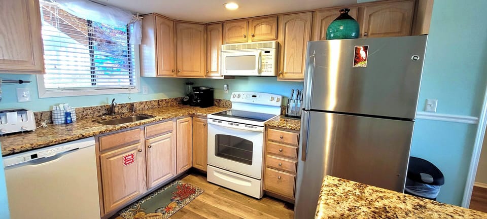 Your fully equipped kitchen features granite countertops, stainless steel appliances, and warm wood cabinets—perfect for preparing meals with everything you need at your fingertips.