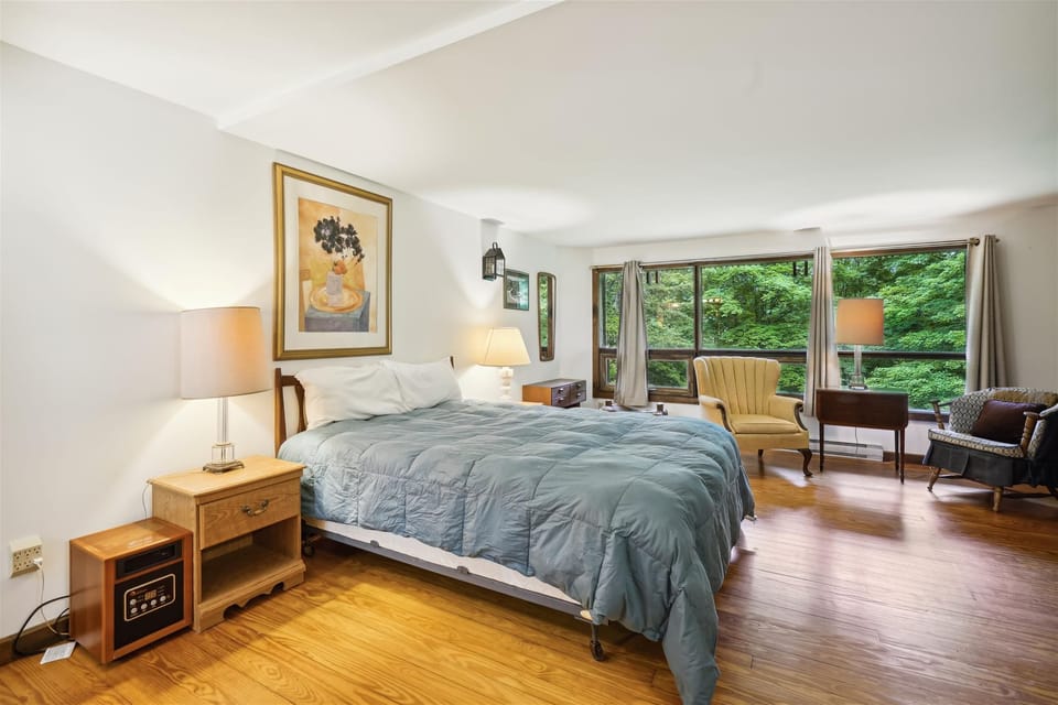 Primary Bedroom Retreat - Spacious and inviting, this bedroom offers plenty of room to relax while enjoying peaceful woodland views through the large windows.