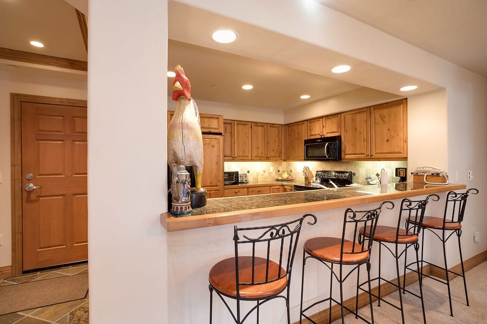 Your fully equipped kitchen features warm wood cabinetry, granite counters, and a breakfast bar perfect for morning coffee or casual meals.