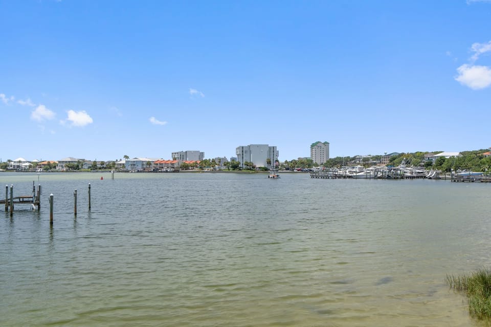 Waterfront community with coastal homes, high-rise buildings, and marina docks along calm bay waters under clear blue skies.