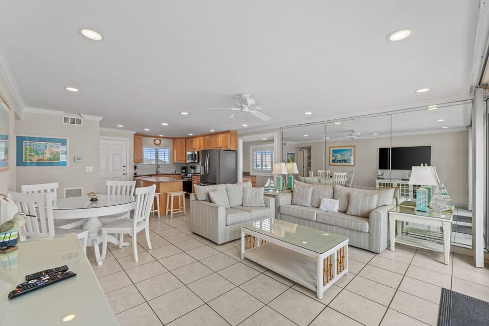 Relax in your spacious open-plan living area featuring modern coastal furnishings, fully equipped kitchen, and comfortable seating perfect for family gatherings.