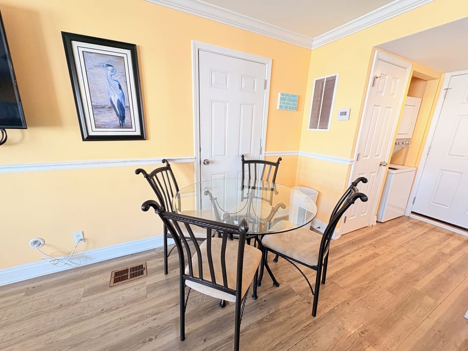 Gather around your elegant glass dining table for memorable meals in this bright, inviting space with warm yellow walls and polished floors.