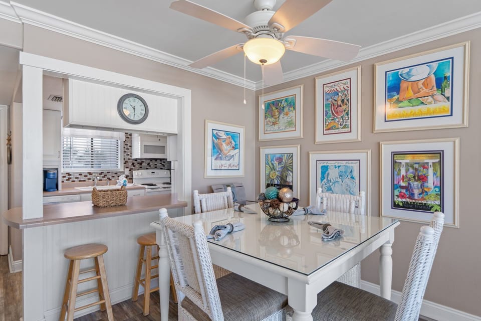 Your dining area features a glass-top table with wicker seating and vibrant artwork creating a bright, welcoming space.