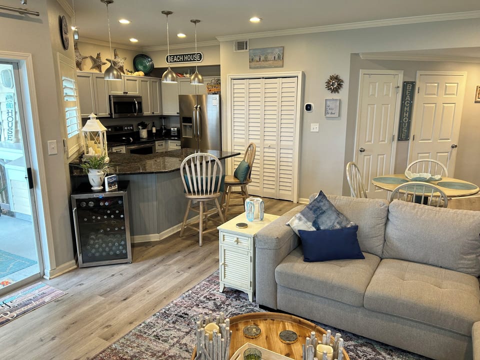 Sink into your cozy living room where coastal charm meets modern comfort, complete with a fully equipped kitchen for your culinary adventures.