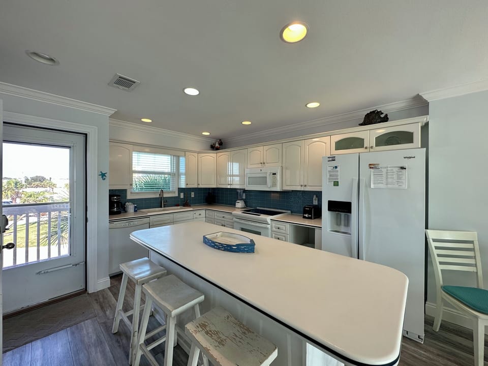 Your fully equipped kitchen awaits with spacious counters, modern appliances, and ocean views through the sliding door to your private balcony.