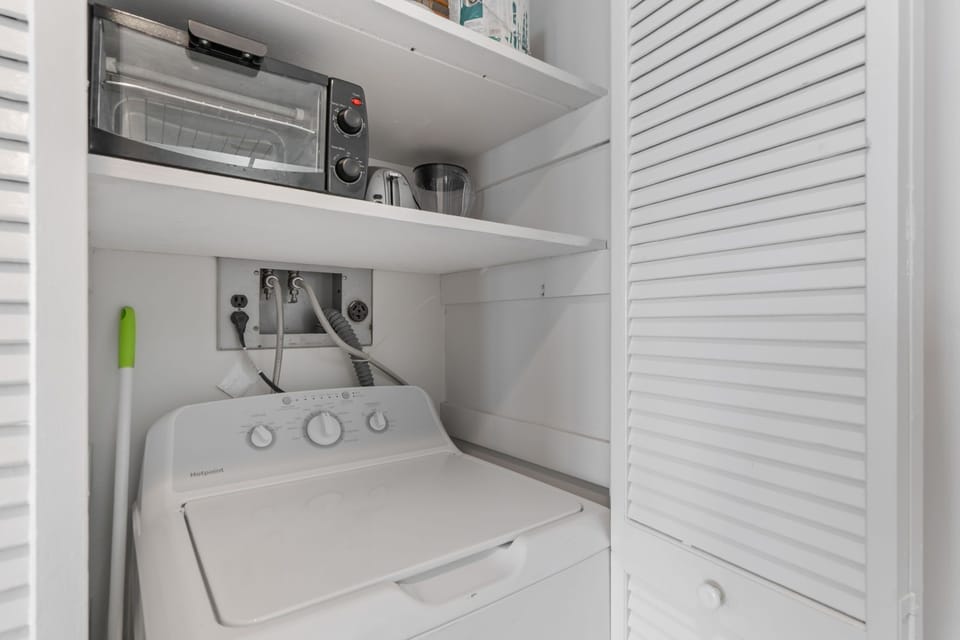 Your compact laundry closet keeps everything organized with a full-size washer, toaster oven, and essential cookware all within easy reach.