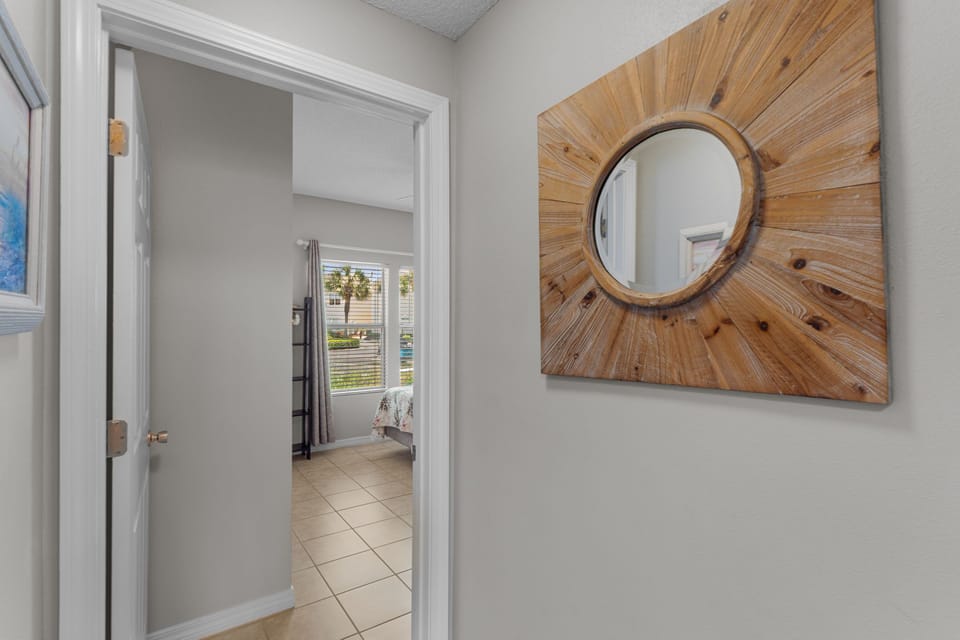 A charming sunburst mirror greets you in this welcoming hallway, where sunlight filters through nearby windows and reflects the ease of coastal living.