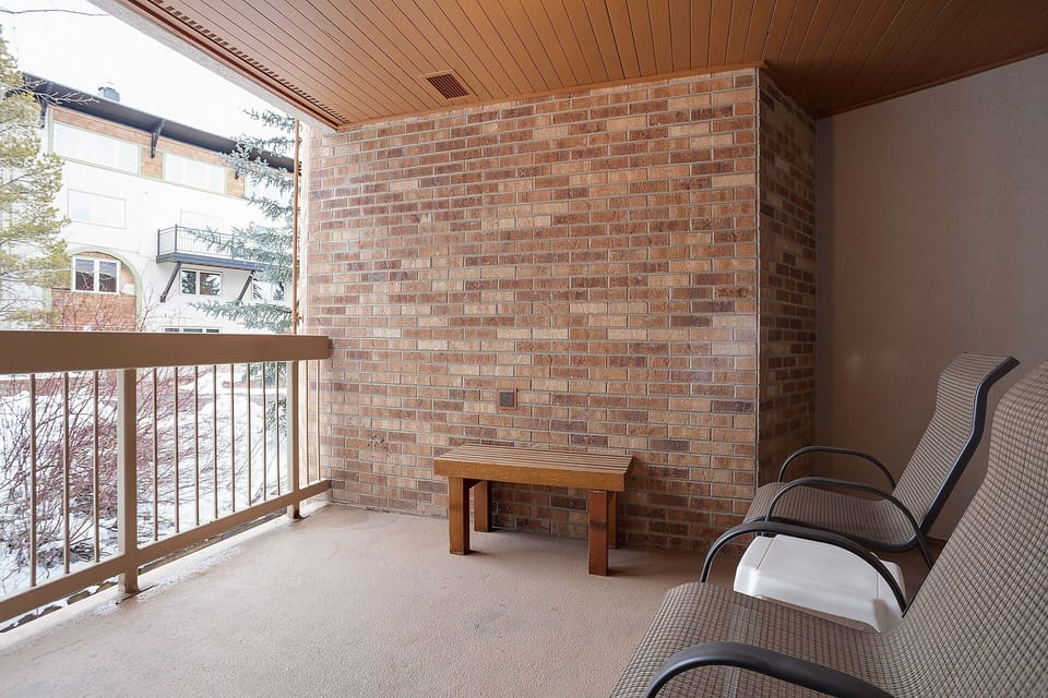 Your private balcony features comfortable seating and a warm wooden table, perfect for morning coffee while enjoying peaceful neighborhood views.